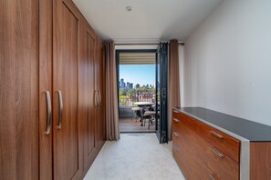 Ein Korridor, der zu einem Balkon mit Blick auf die Stadt führt, mit einem Holzschrank und einem kleinen Tisch mit Stühlen.