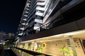 A modern building with multiple balconies, a glass facade, and a sign with directional arrows. - Studio Moderno - Oscar Freire (São Paulo)