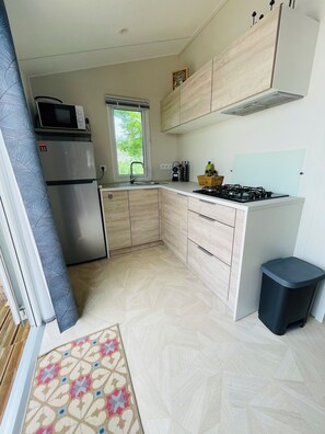 A compact kitchen with a refrigerator, microwave, sink, and gas stove. - 4-person mobile home in a family campsite in the mountains  (Saillagouse)