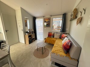 A modern living room with a sofa, a small round table, and a bookshelf. - 4-person mobile home in a family campsite in the mountains  (Saillagouse)