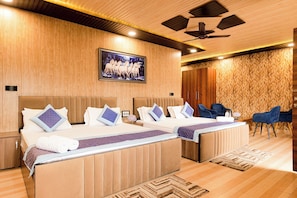 A hotel room with two beds, a ceiling fan, a mounted TV, and a patterned wall. - Aarohan - By Shivaneel Hospitality (Dhari)