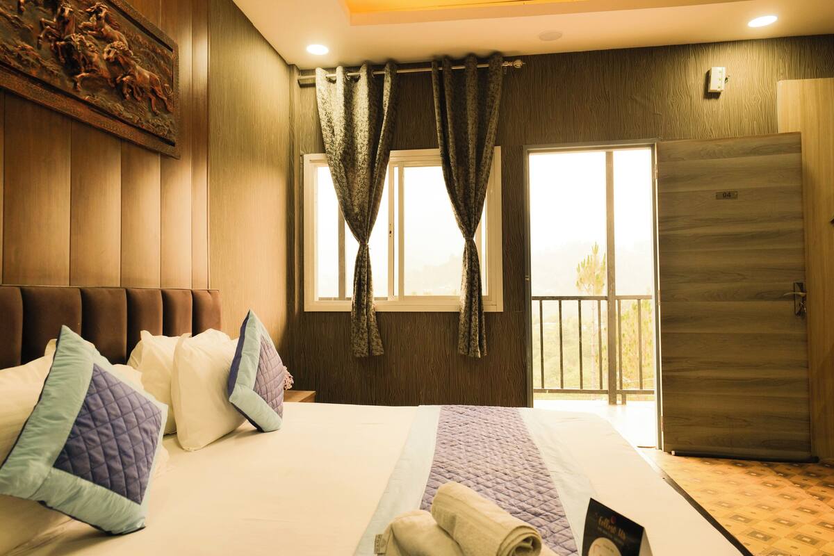 A hotel room with a bed, curtains, a door, and a window.