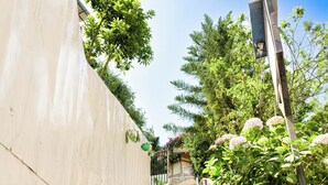 Unos escalones de piedra conducen a un edificio con una pared blanca a un lado y otra de ladrillo, adornados con macetas a lo largo de los escalones.