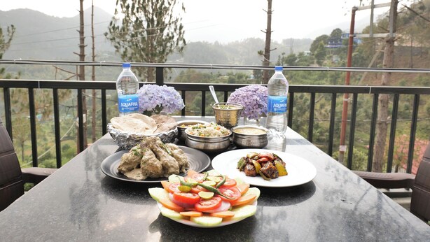 Una mesa con varios platos, una botella de agua y vistas al exterior.