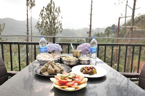 A table with various dishes, a water bottle, and a view of the outdoors. - Aarohan - By Shivaneel Hospitality (Dhari)