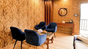 Una habitación con pared de diseño estampada en patrón de espiga, un escritorio de madera con espejo, dos sillas azules y una cama con cabecera blanca.