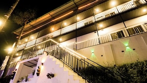 Un edificio de varios niveles con balcones, escaleras e iluminación exterior.