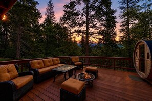 Eine Terrasse mit Gartenmöbeln, einer Feuerstelle und einem Holzfass.