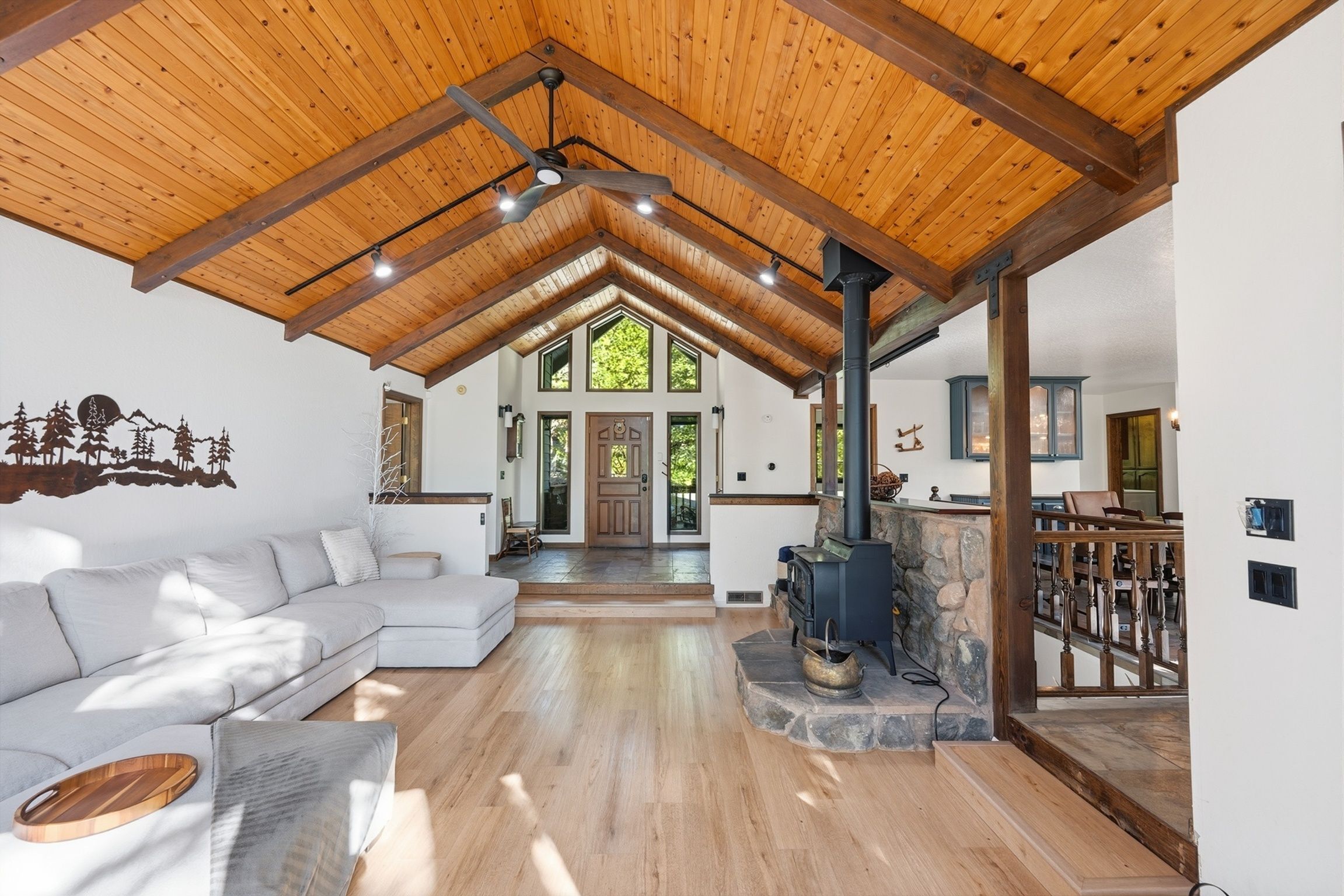 Un vaste espace de vie doté d’un plafond en bois, d’une cheminée et d’une grande fenêtre.