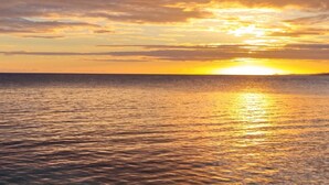 Un coucher de soleil sur une mer calme, avec un horizon dégagé.