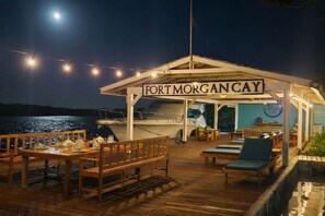 A wooden deck with a covered seating area, a sign reading 'FORT MORGAN CAY,' and a view of the water. - Fort Morgan Cay, Roatan: 40-Acre Private Island from 10-20 Guests - 8 Bedrooms (Roatan)