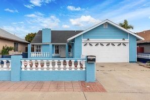 A two-story house with a garage, a blue exterior, and a white garage door. - Spacious 3BR San Diego Home w/ Parking & AC Modern (San Diego)
