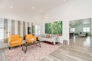 A spacious living area with a large mirror, a sofa, two armchairs, a coffee table, and a large painting of a forest. - Spacious 3BR San Diego Home w/ Parking & AC Modern (San Diego)