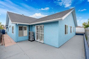 Ein eingeschossiges Haus mit blauer Fassade, einer Garagentür und einer kleinen Klimaanlage.