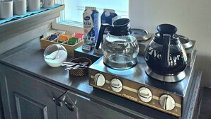 Una cocina con ventana, cafetera, cartones de leche y un cartel en la pared.