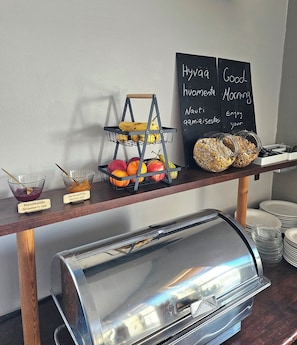 Presentación de bufé de desayuno con frutas, mermeladas y opciones de café.