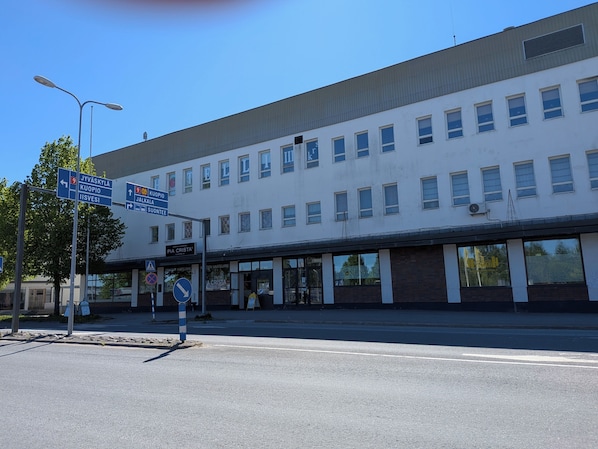 A building with multiple windows and a sign indicating directions to various locations. - Hotelli Suonenjoki (Suonenjoki)