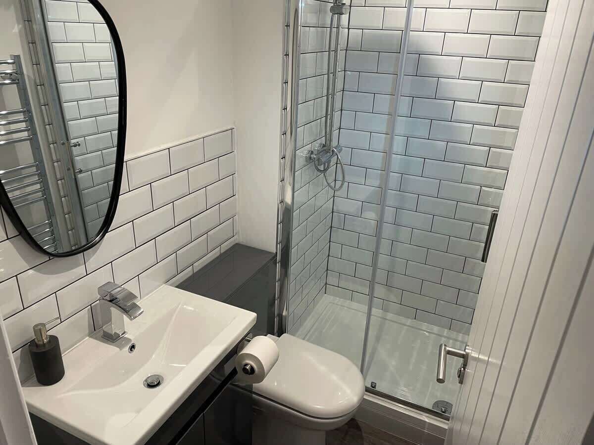 A bathroom with a white sink, mirror, and glass shower enclosure.