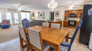 A dining area with a wooden table and chairs, a chandelier, and a kitchen with wooden cabinets and appliances.