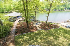 A lakeside property with a covered patio, a hot tub, and a well-maintained lawn.