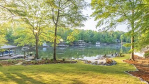 A lakeside view with docked boats, a gazebo, and a grassy area.