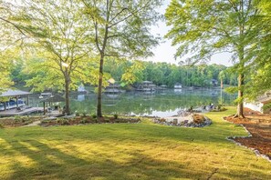 A lakeside view with docked boats, a gazebo, and a grassy area.
