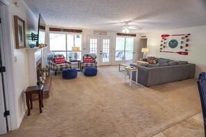 A living room with a gray sofa, blue bean bag chairs, a small table, and a ceiling fan.