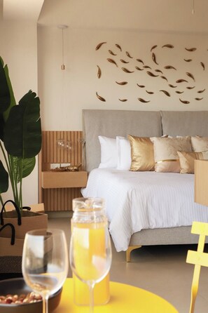 Ein modernes Schlafzimmer mit einem Bett, Nachttischen, einer großen Pflanze und einem gelben Tisch mit einem Glas und einer Flasche.