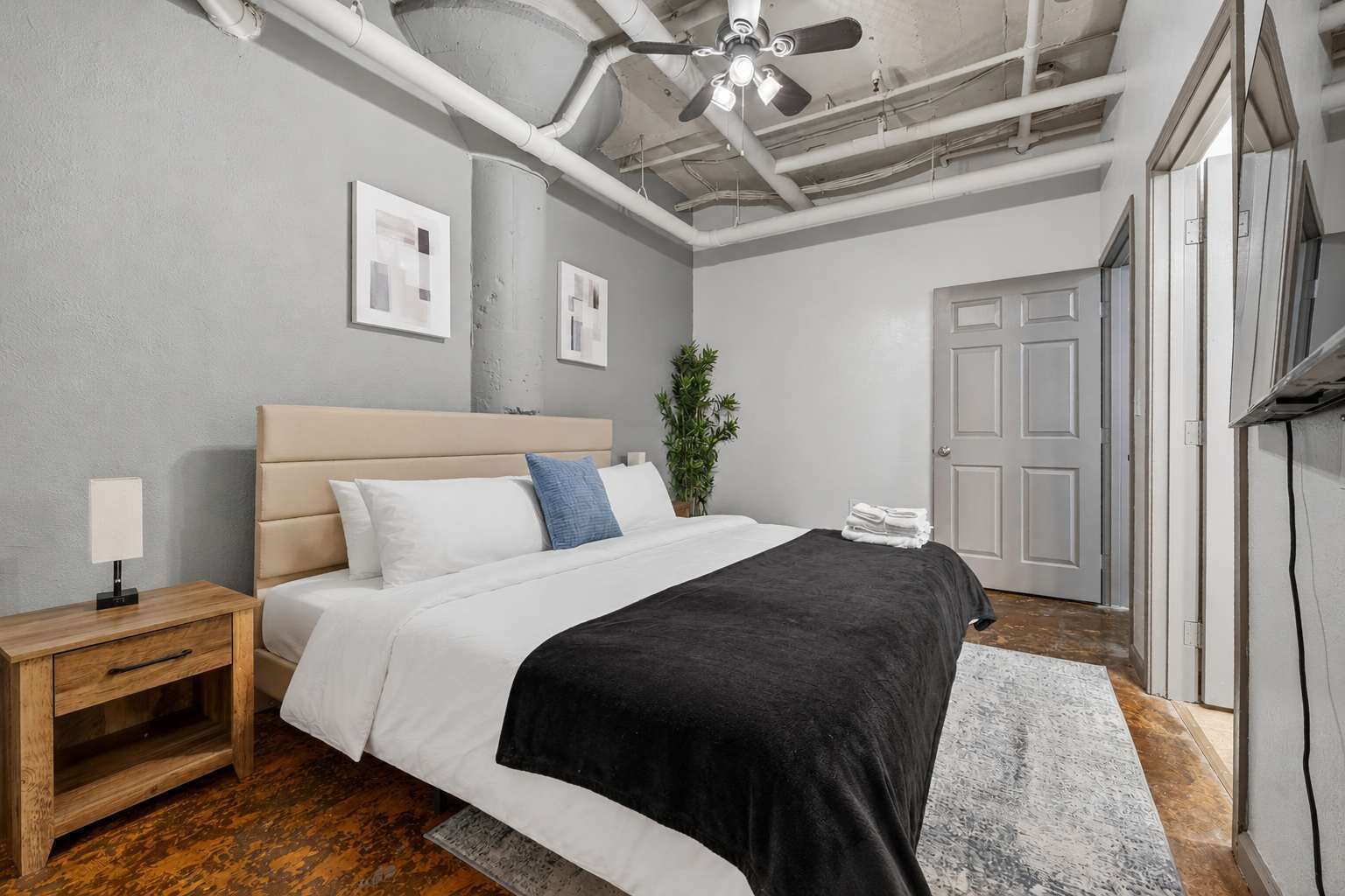 A modern bedroom with a bed, bedside table, and a ceiling fan.