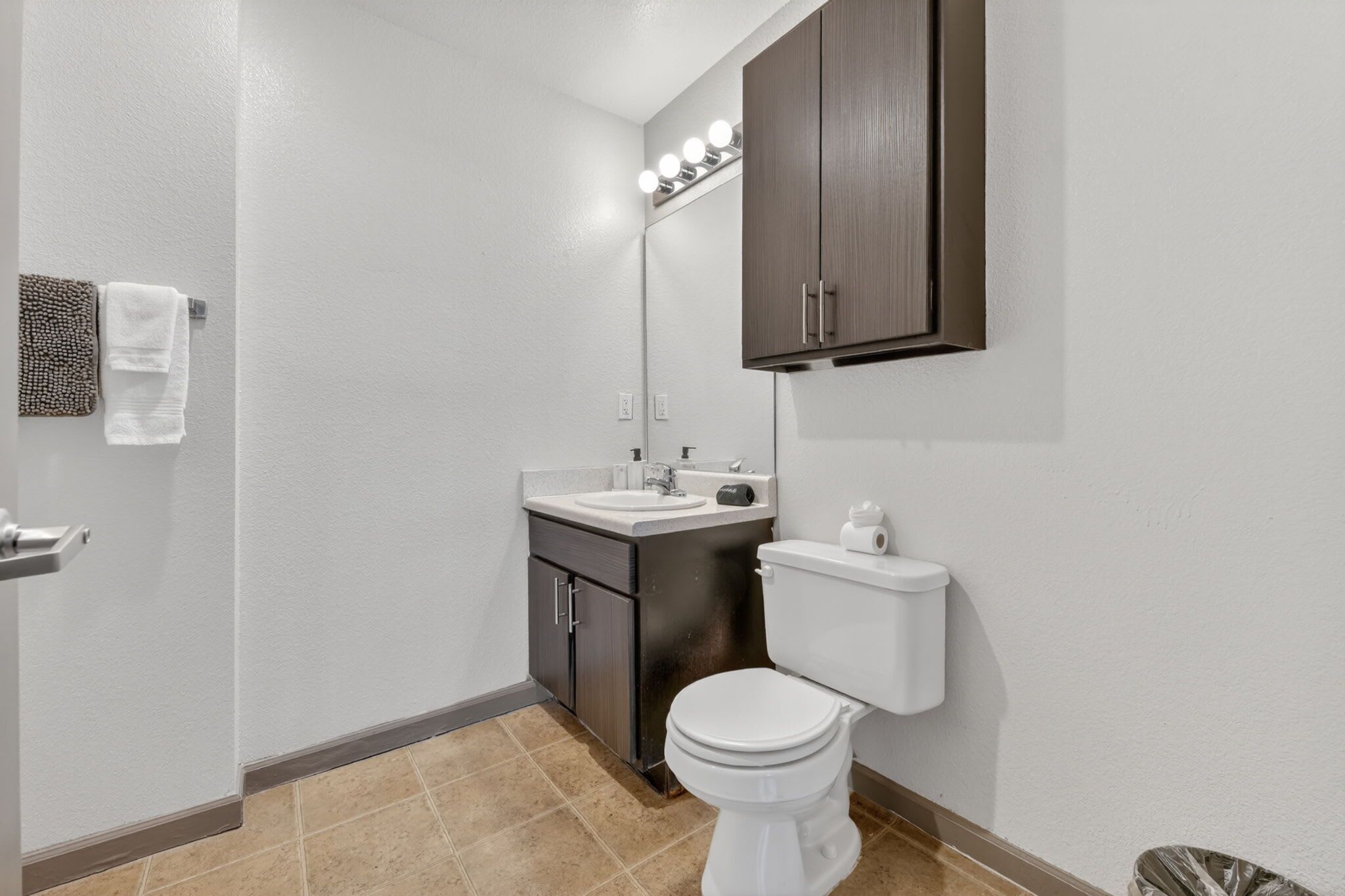 A bathroom with a toilet, sink, mirror, and towel rack.