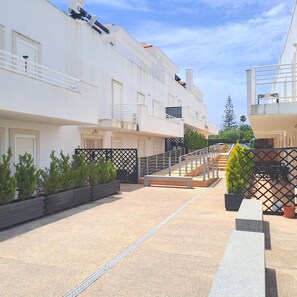 A residential building with balconies, a paved courtyard, and potted plants. - 1-Bedroom Apartment Near the Beach in Cabanas with a Parking Space (Cabanas de Tavira)