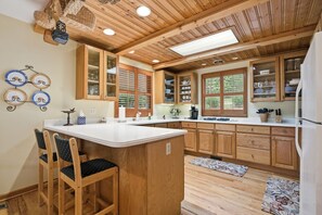 Een keuken met houten kastjes, een centraal eiland en een eetgedeelte met stoelen.