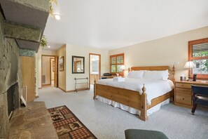 A bedroom with a large bed, a desk, a chair, a mirror, and a fireplace. - Lakefront Lodge w Dock, Fire Pit & Views! (Cullowhee)