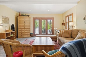 Un salón acogedor con una mesa de centro de madera, sillas de mimbre, un sofá y una mesa de comedor.