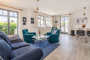 Un salon moderne comprenant un canapé, deux fauteuils, une table basse et un coin repas avec une table et des chaises.