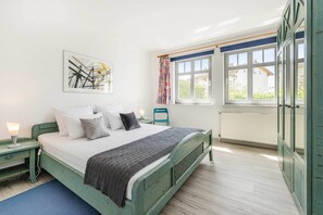 Une chambre à coucher avec un lit, une table de chevet, une fenêtre et un radiateur.