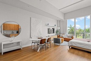 Ein modernes Hotelzimmer mit Essbereich, einem Bett, einem Fernseher und einem Balkon mit Aussicht.
