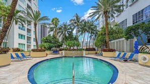 A pool area with a circular pool, palm trees, and lounge chairs. - Bayfront Vizcayne Condo w/ Pool & Free Parking (Miami)