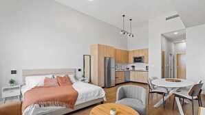 A modern bedroom with a bed, bedside tables, a round wooden coffee table, and a gray armchair. - Bayfront Vizcayne Condo w/ Pool & Free Parking (Miami)