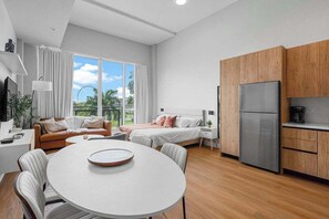 Ein modernes Zimmer mit Bett, Esstisch und Küchenzeile.