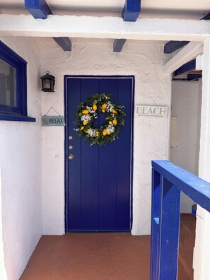 A blue door with a wreath, a 'BEACH' sign, and a 'RELAX' sign.