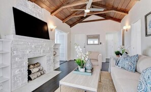 A living room with a fireplace, a ceiling fan, and a sofa.