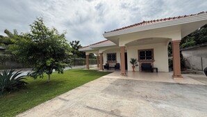 Un patio techado con piso de baldosas, mobiliario exterior y una planta en maceta.