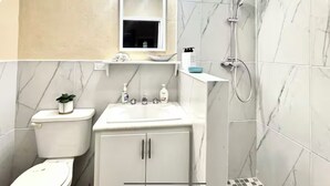 Ein Badezimmer mit Toilette, Waschbecken, Schrank, Spiegel und Dusche.