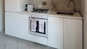 Eine moderne Küche mit weißen Schränken, einem Gasherd, einem Backofen und einem Spülbecken.