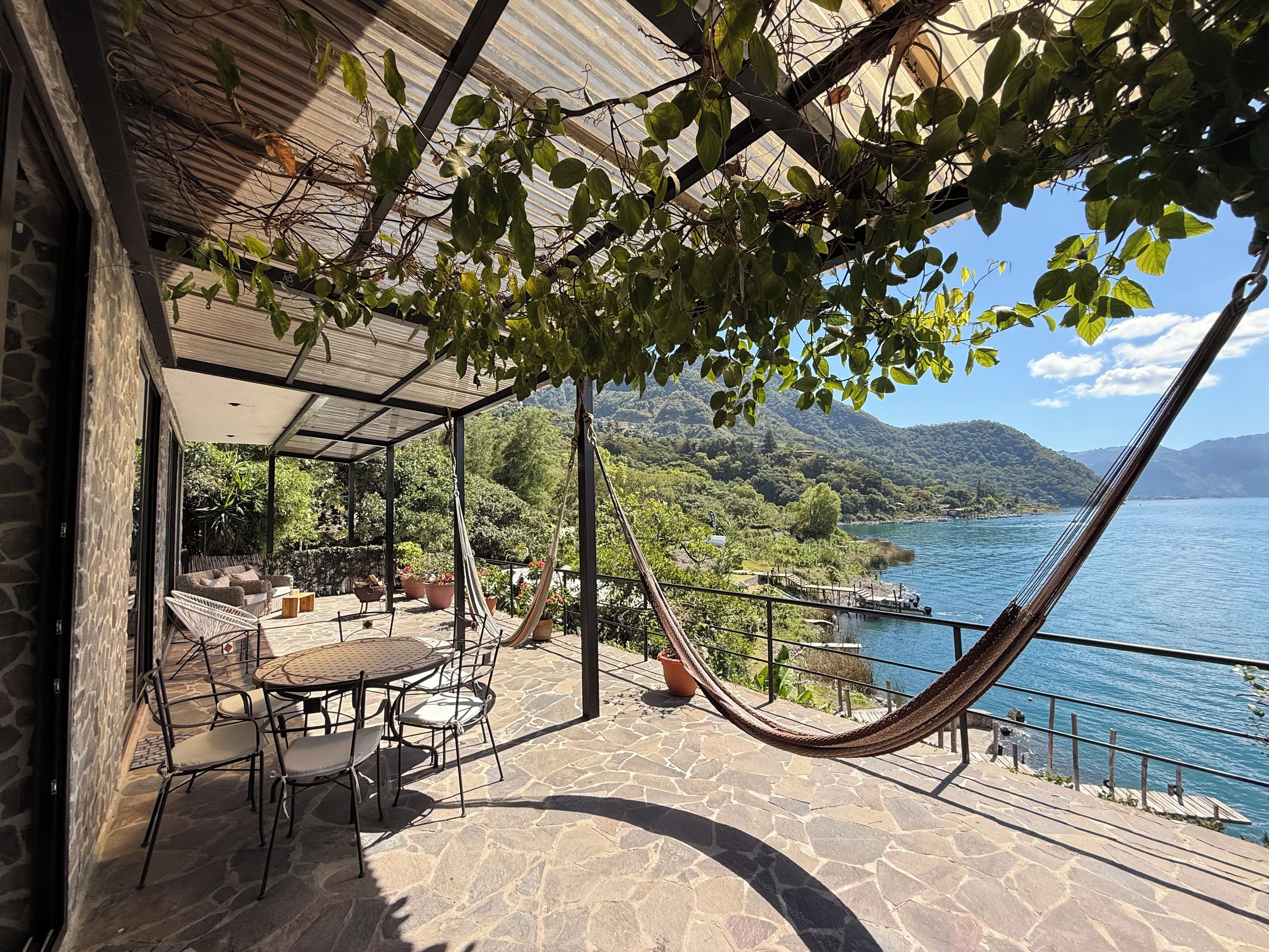 Una terrazza esterna con pavimento in pietra, un'amaca e un tavolo con sedie.