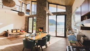 Amplia sala de estar con mesa de comedor, sofá y zona de cocina con vista al lago.