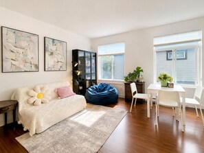 Ein modernes Wohnzimmer mit einer Couch, Sitzsack, Esstisch, Stühlen und Kunstwerken an den Wänden.