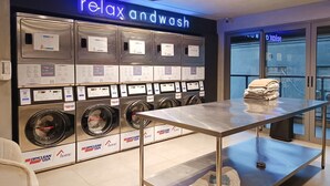 Ein moderner Waschraum mit mehreren Waschmaschinen und einem Tisch mit gefalteter Kleidung.