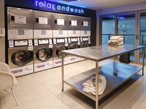Ein moderner Waschraum mit mehreren Waschmaschinen und einem Tisch mit gefalteter Kleidung.